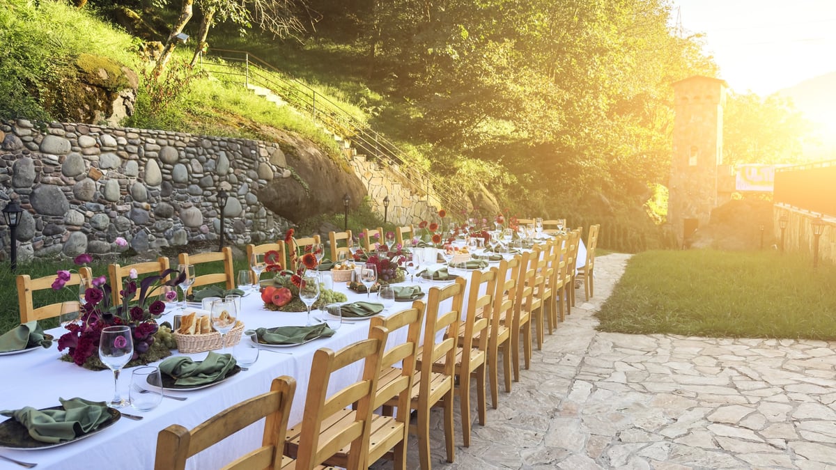 Beautifully set outdoor dining table in a Mediterranean garden, with flowers and glassware, warm evening light